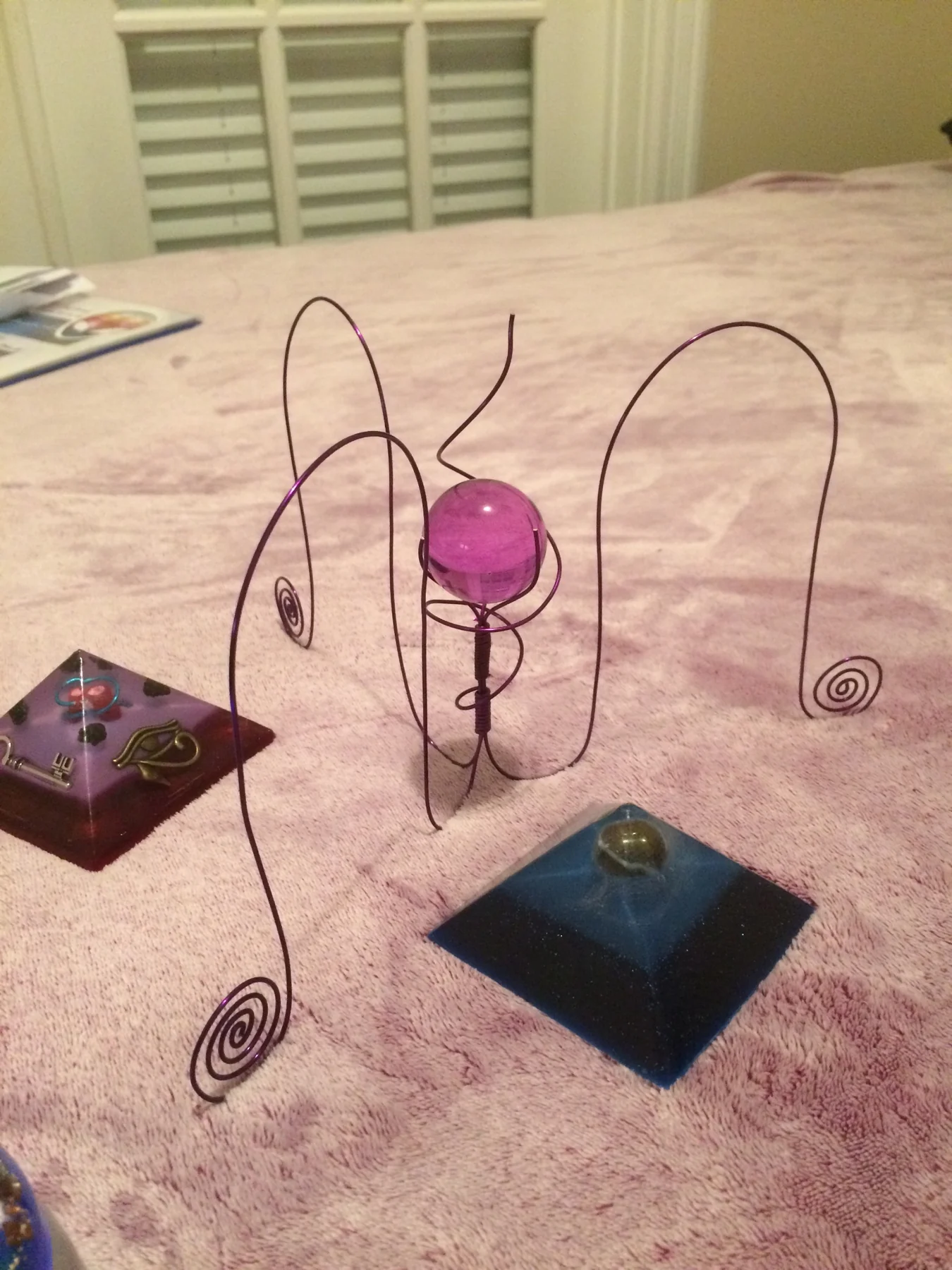 Wire sculptures displayed with resin pyramids