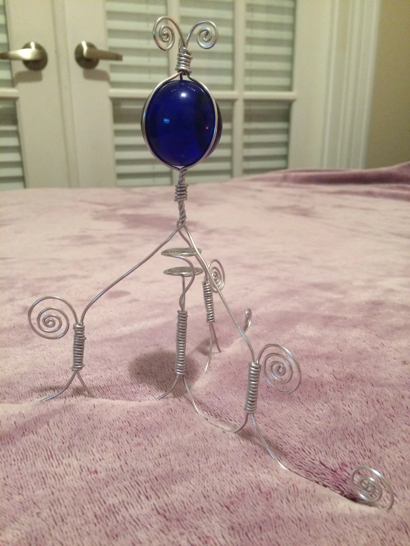 Wire figure sculpture with blue oval form