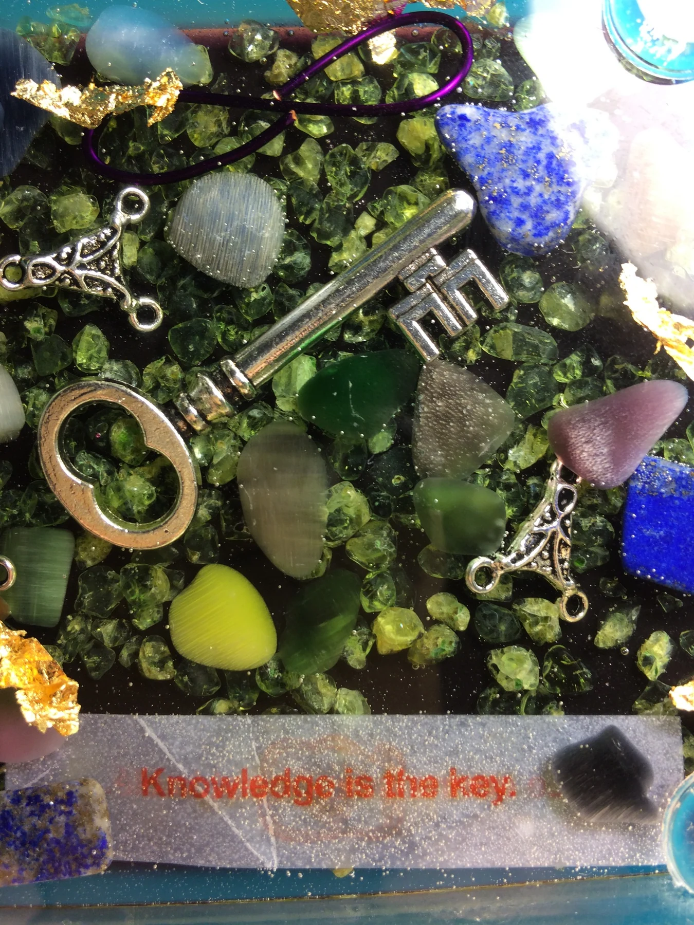 Resin detail with embedded stones, key and the words Knowledge is the key