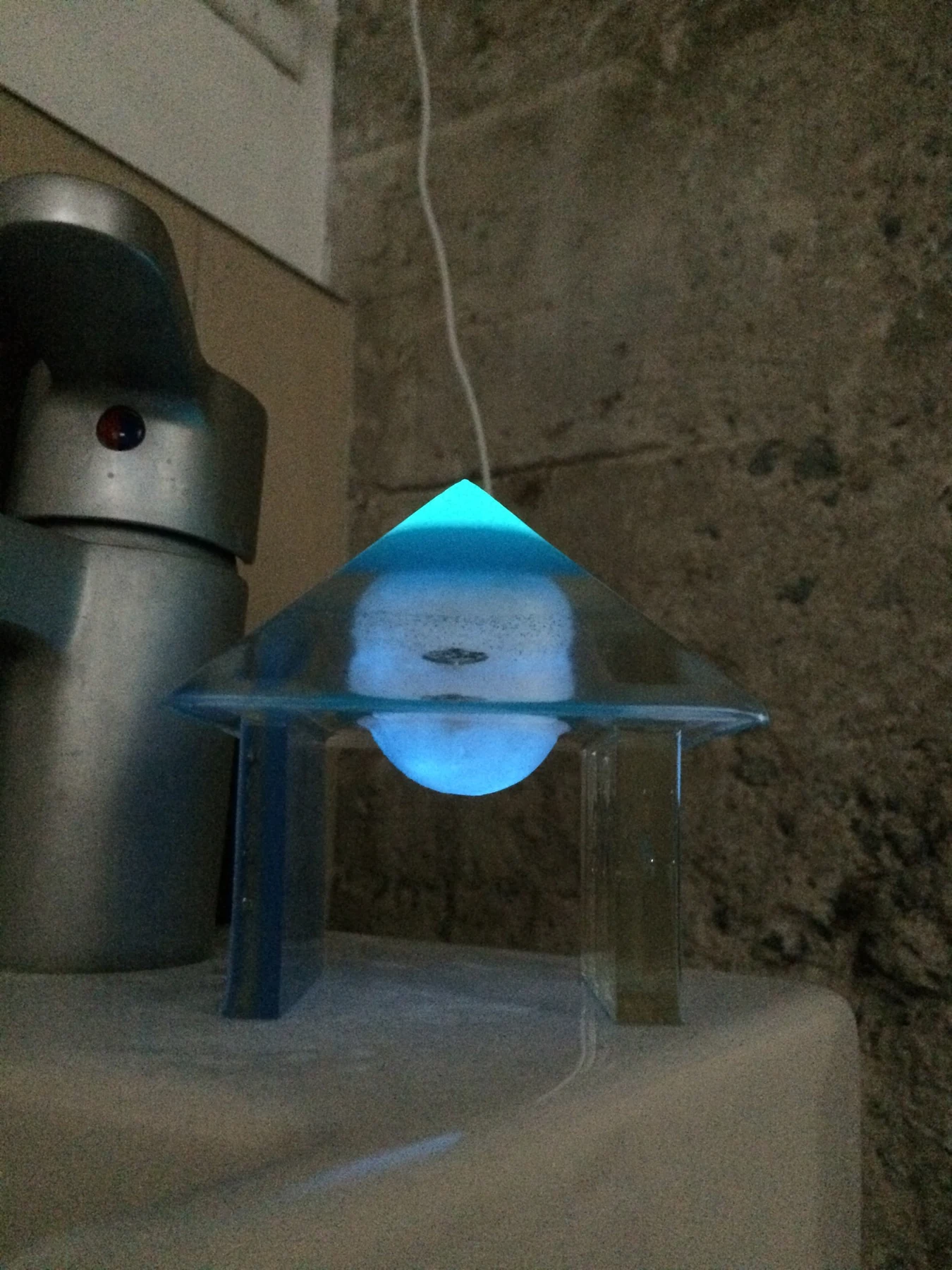 Blue illuminated resin pyramid on a clear stand