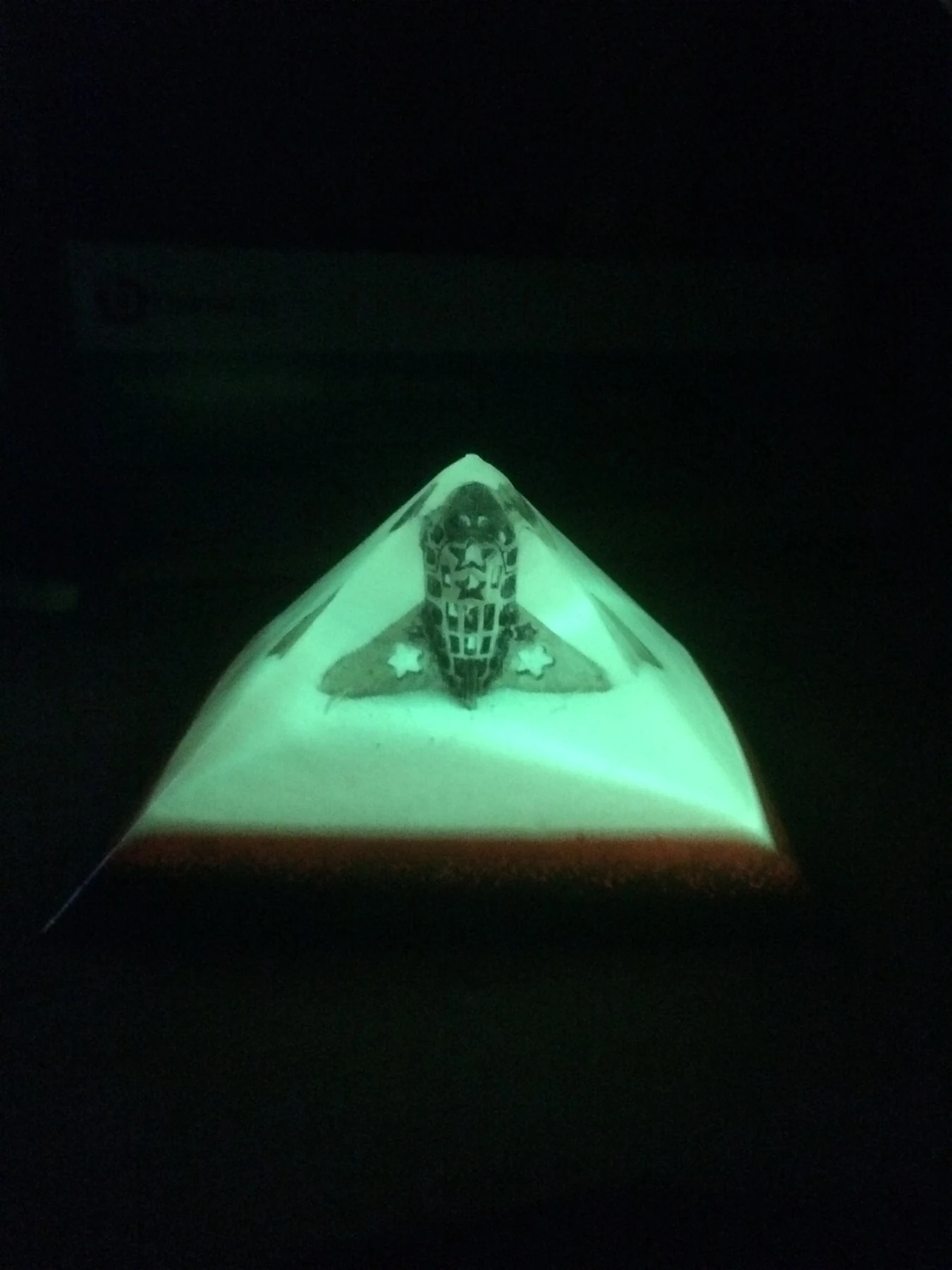 Green illuminated resin pyramid with embedded symbolic object